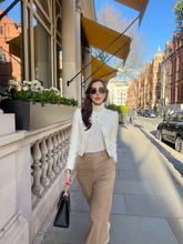 a lady wears a white wool jacket with light brown loose fit pants